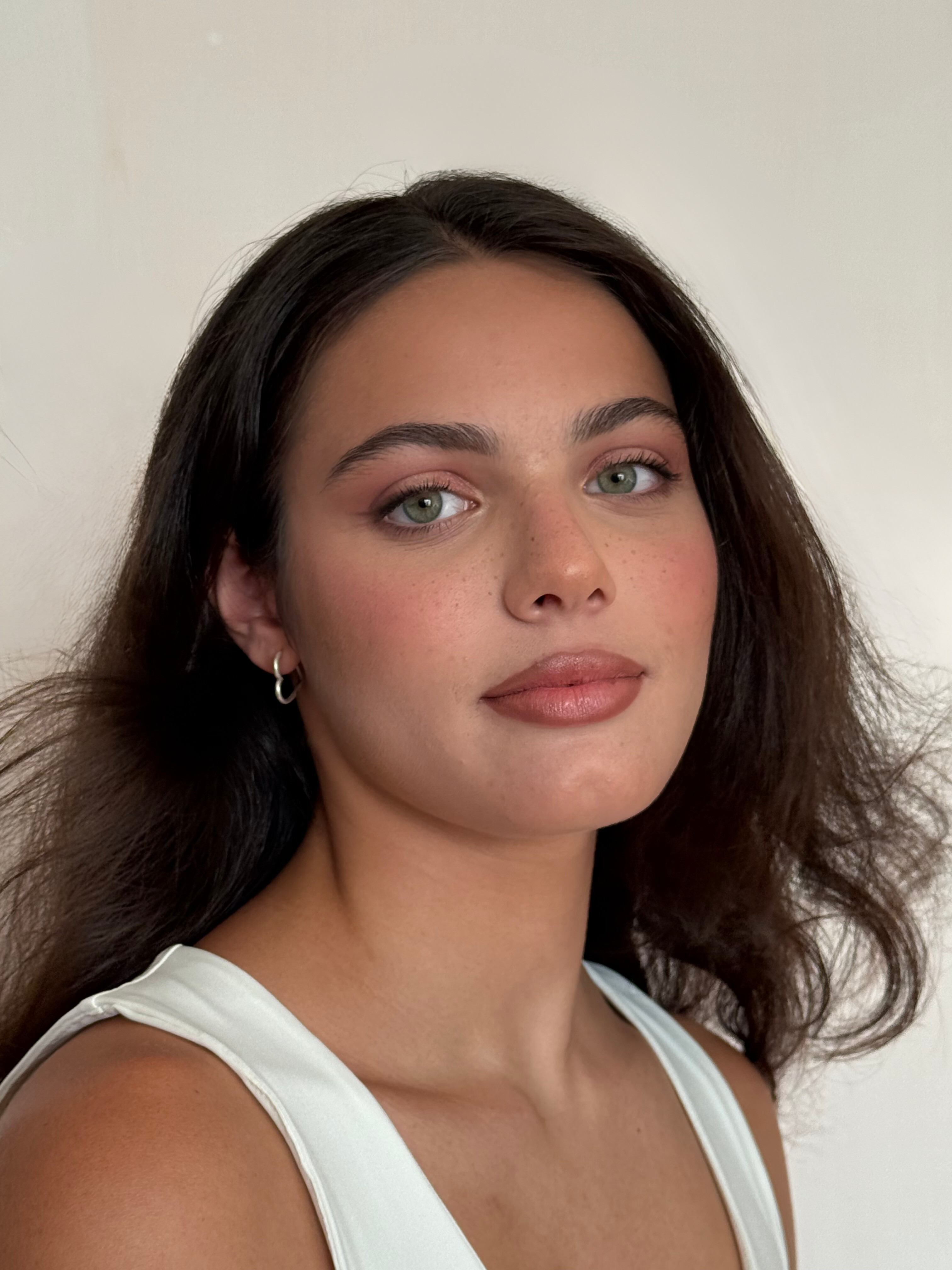 A fresh and refined bridal look: glowing skin, softly defined eyes in rosy tones, and nude lips for timeless natural elegance.